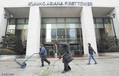 موظف (وسط) من مجموعة كومهو للنظافة يمشي أمام مقر الشركة في سيئول أمس، مجموعة كومهو التي تعد من أكبر تسع شركات في مجال النشاطات ا