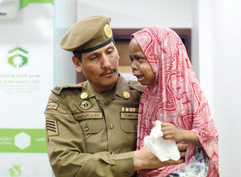 رجل أمن يحمل طفلة تائهة في الحرم المدني