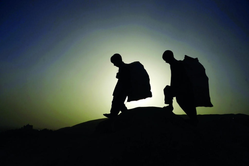 طفلان في أفغانستان دفعهم الفقر المدقع إلى العمل في حمل أكياس القمامة