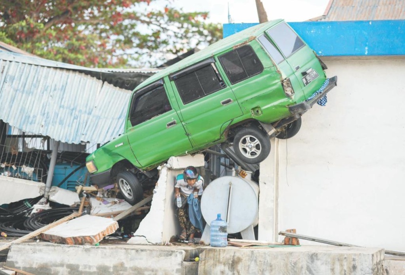 أحد الناجين يسير تحت سيارة قذفت من أعلى مبنى في بالو