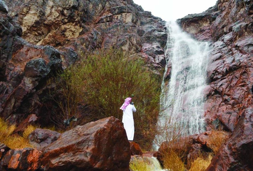 رجل يلتقط صورة لجريان سيل في أحد الأودية في المدينة المنورة