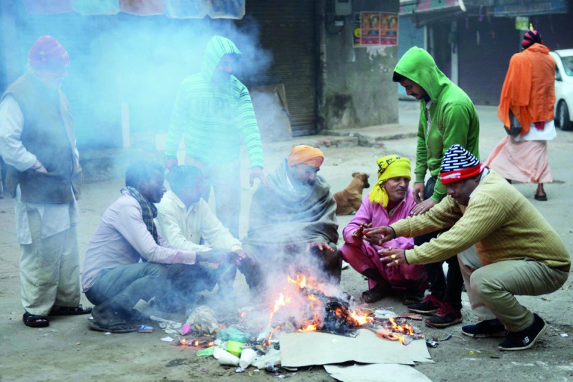 هنود يشعلون النار في مخلفات مضطرين بحثا عن الدفء