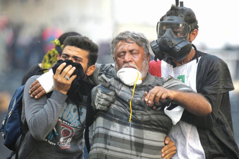 عراقيان يساعدان متظاهرا تأثر بالغاز المسيل للدموع الذي أطلقته قوات الأمن