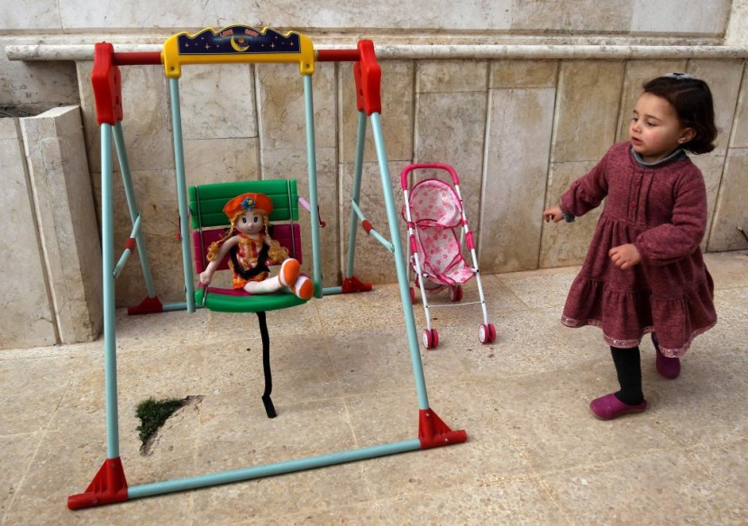 ضحكات سلوى تصدح مع كل غارة.. هكذا يحمي أب ابنته في إدلب