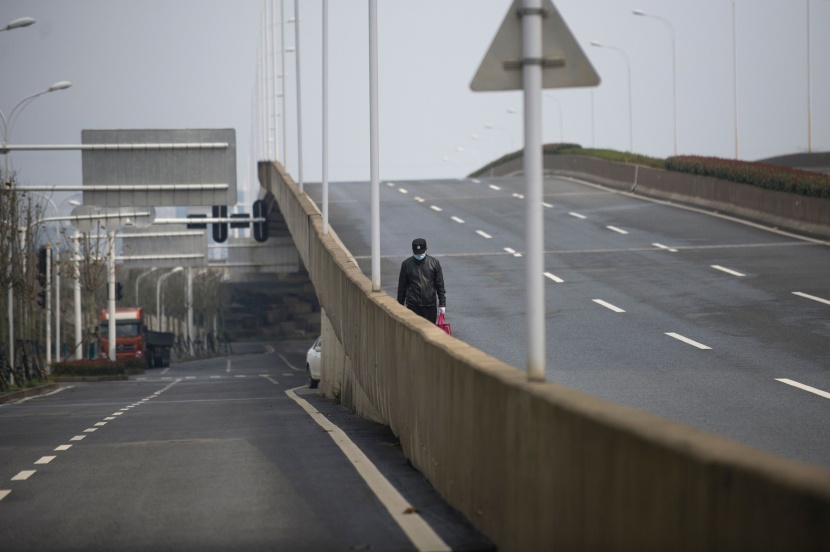 رجل يسير في شارع فارغ بمدينة ووهان التي تخلو من المارة خوفا من "كورونا"