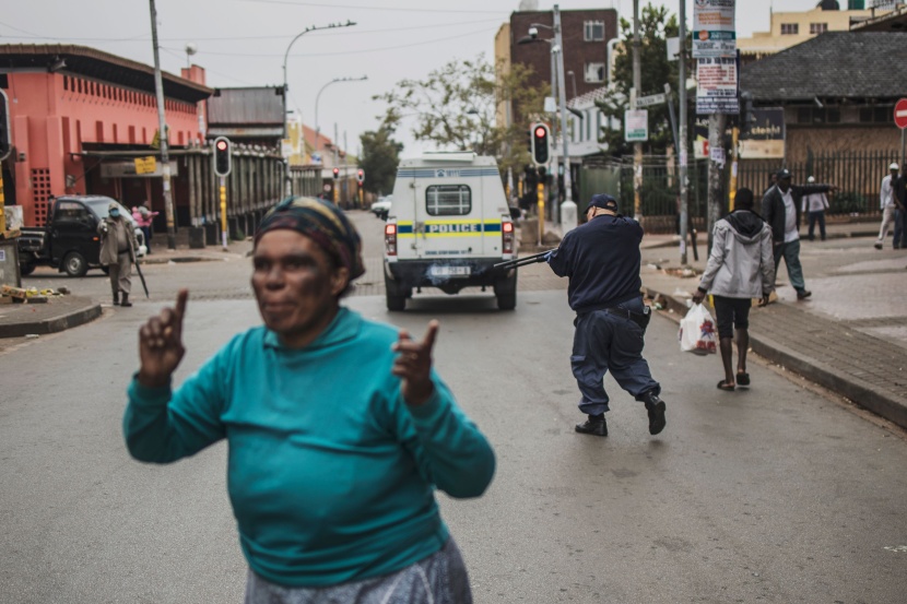 شرطي يوجه بندقيته تجاه المتسوقين لحثهم على فرض مسافة آمنة بينهم في جنوب إفريقيا