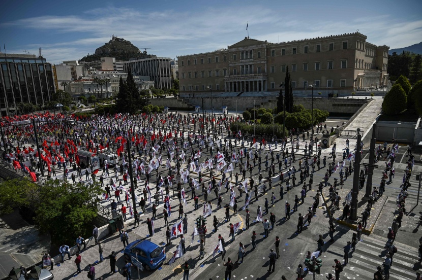 عمال وطلبة يونانيون يرتدون كمامات وقفازات خارج مبنى البرلمان احتفالا بعيد العمال .
