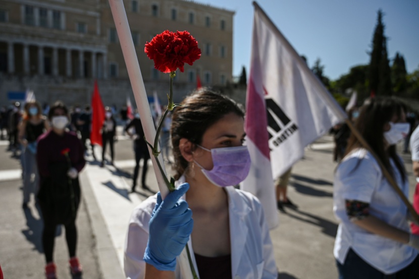 عمال وطلبة يونانيون يرتدون كمامات وقفازات خارج مبنى البرلمان احتفالا بعيد العمال .