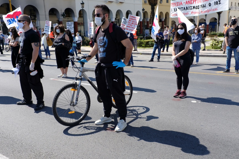 عمال وطلبة يونانيون يرتدون كمامات وقفازات خارج مبنى البرلمان احتفالا بعيد العمال .