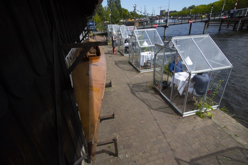 غرف زجاجية حول كل طاولة للابقاء على مسافات آمنة بين طاولات الزبائن في أمستردام   .