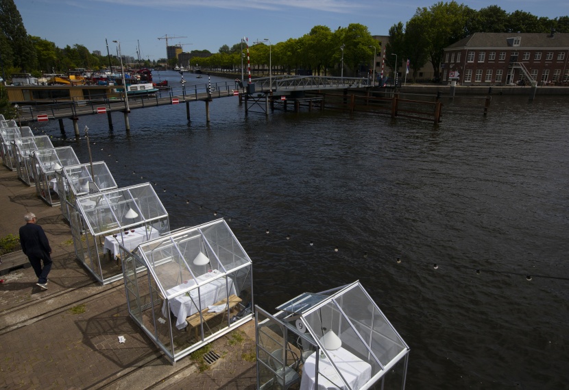 غرف زجاجية حول كل طاولة للابقاء على مسافات آمنة بين طاولات الزبائن في أمستردام   .