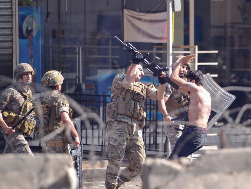 متظاهر لبناني يتلقى ضربة من جندي خلال تظاهرات في مدينة طرابلس