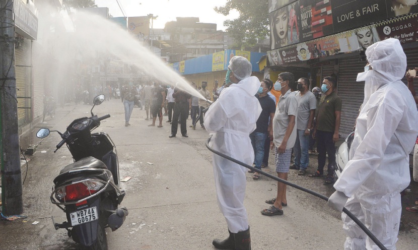 رجلان يرتديان ملابس واقية يقومان بعمليات تطهير مكثفة في مدينة سيليجوري الهندية