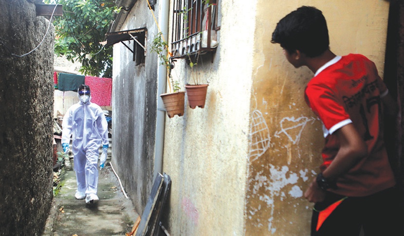 أحد العاملين في مجال الرعاية الصحية يمشي في زقاق في منطقة عشوائية في مدينة مومباي 