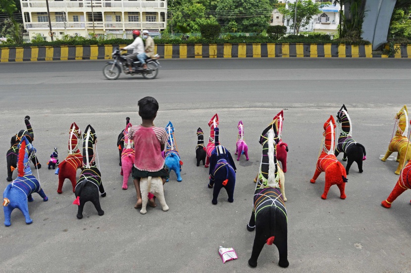 لجذب العملاء.. طفل بائع يجلس على لعبة محشوة على الطريق في حيدر أباد