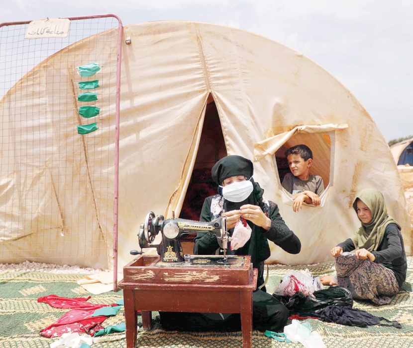 امرأة سورية تخيط كمامات في مخيم للنازحين قرب إدلب شمال غربي سوري