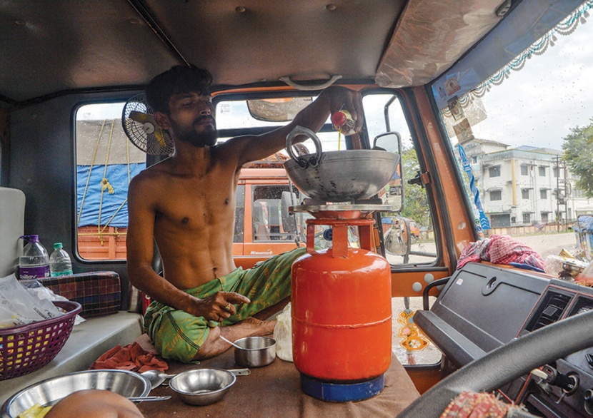 سائق يعد الطعام داخل شاحنته بعدما تقطعت به السبل إثر الإغلاق الذي فرضته الحكومة الهندية في البلاد