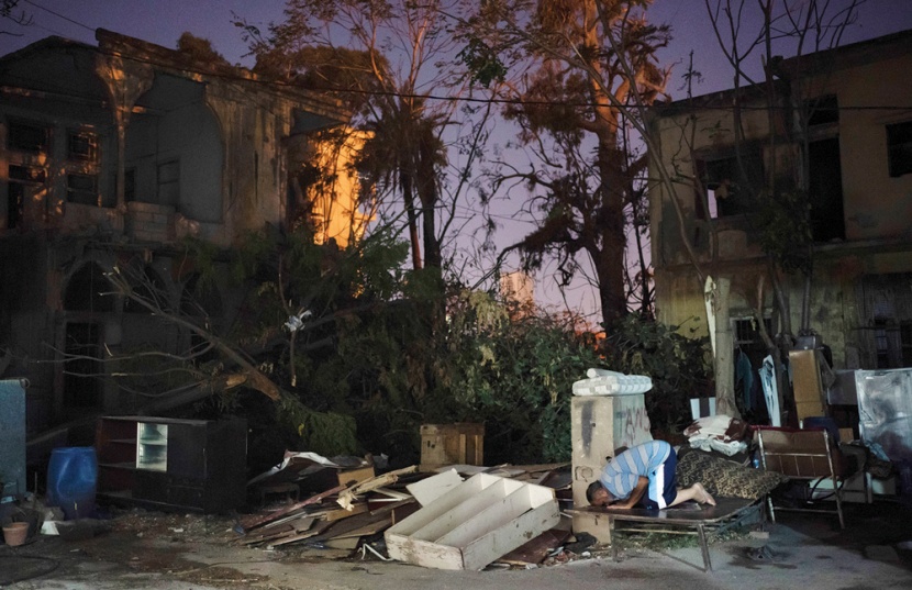 لبناني يصلي على سرير مؤقت بجوار أنقاض منزله الذي دمر في انفجار مرفأ بيروت