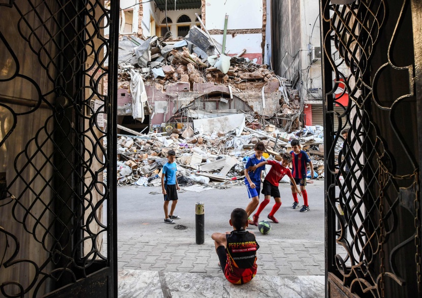 أطفال يلعبون كرة القدم وسط شارع خلفه الدمار بعد انفجار بيروت 