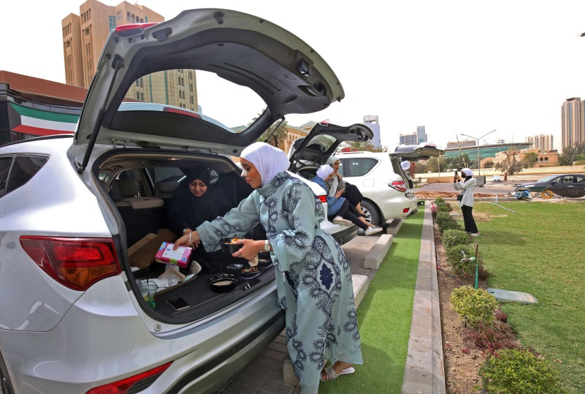 كويتيون يتناولون الطعام داخل سيارتهم بعد إغلاق المطاعم والمقاهي بسبب تفشي كورونا