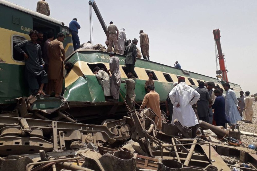 أفراد من الأمن ومتفرجون في موقع حادث قطار في منطقة داهركي في إقليم السند الشمالي في باكستان، حيث قتل 34 شخصا على الأقل وأصيب العشرات. "الفرنسية" قطار الموت