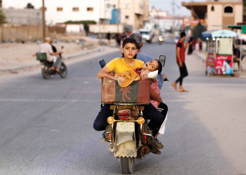 فلسطيني يحمل ولديه على دراجة نارية في أحد شوارع غزة 