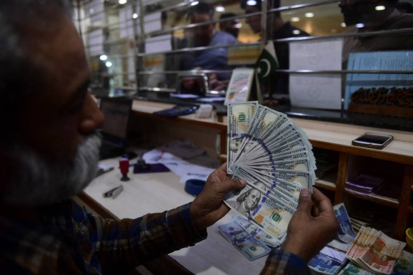 مصرفي يعرض أوراقا من الدولار الأمريكي في سوق للصرافة في كراتشي الباكستانية