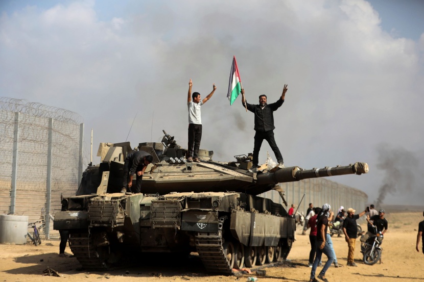 فلسطينيون يحتفلون فوق دبابة إسرائيلية مدمرة في غزة